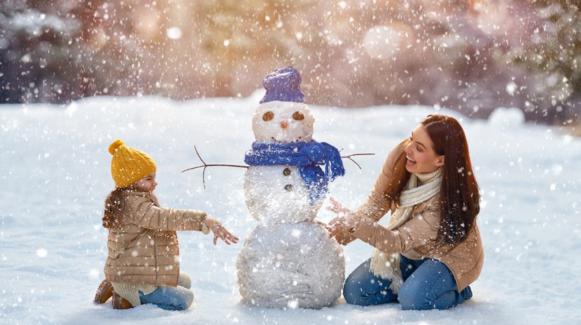 A mother and child build a snowman