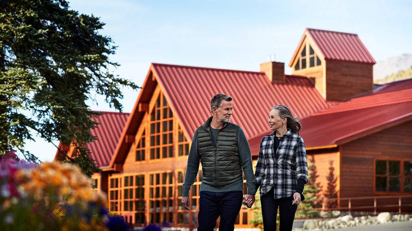 A couple strolls in front of Denali Princess Wilderness Lodge.