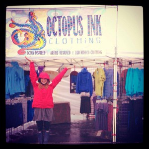 Woman with arms raised in front of booth for Octopus Ink clothing in Anchorage Alaska, Princess Lodges